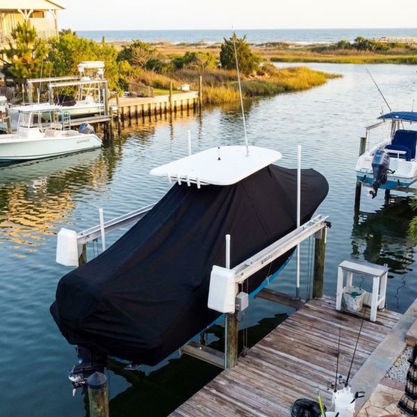 Sea Pro 2100 SV T-Top boat cover in Black Sunbrella fabric on canal lift at Folly Beach, SC