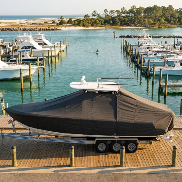Covered motorboat on a trailer parked on a wooden dock at a calm marina
