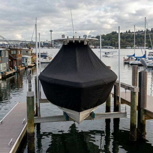 Boat on a motorboat lift covered with a black tarp at a marina, calm water and docks nearby