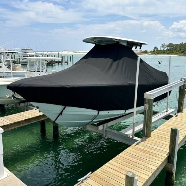 Motorboat covered with a black shelter on a dock at a sunny marina, with calm turquoise water nearby.