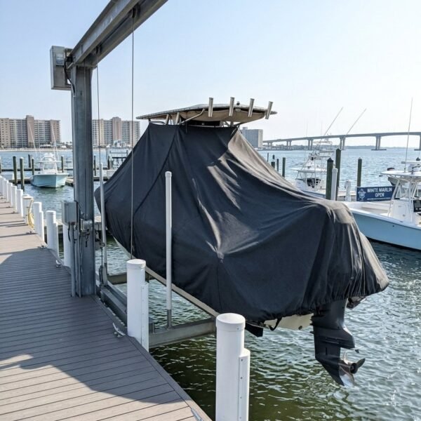 Boat covered with a black tarp on a lift at a marina, prop visible beneath the cover.