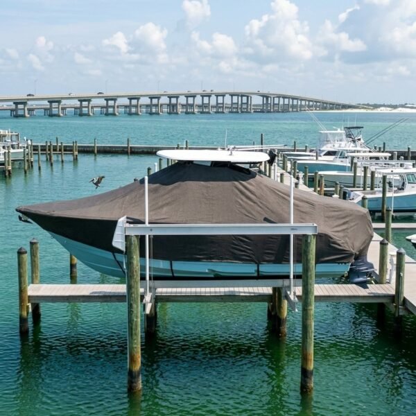 Covered boat on a marina dock with turquoise water and a bridge in the background