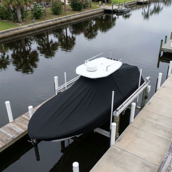 Powerboat on a lift in a calm residential canal, covered with a black protective cover and a white cockpit deck visible on top.