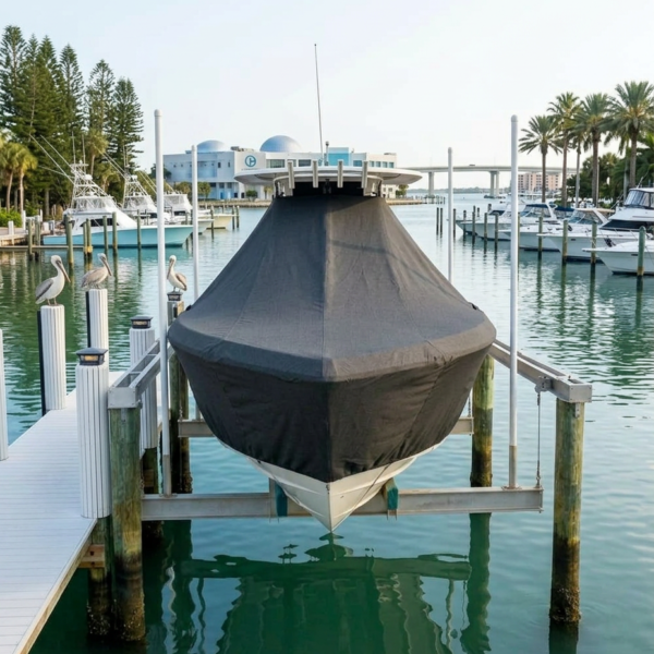 Covered motorboat on a boat lift in a marina, with calm green water and white docks, palm trees, and distant buildings.