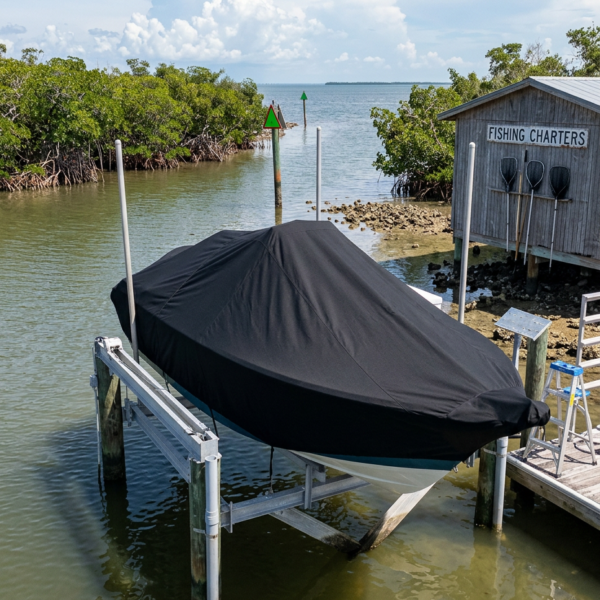 Covered boat on a lift at a dock beside a weathered shack labeled Fishing Charters.