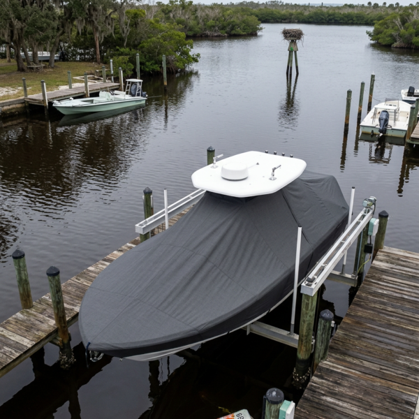 Covered boat on a lift at a wooden dock along a calm river, with pilings and a bird’s nest on a pole in the distance.